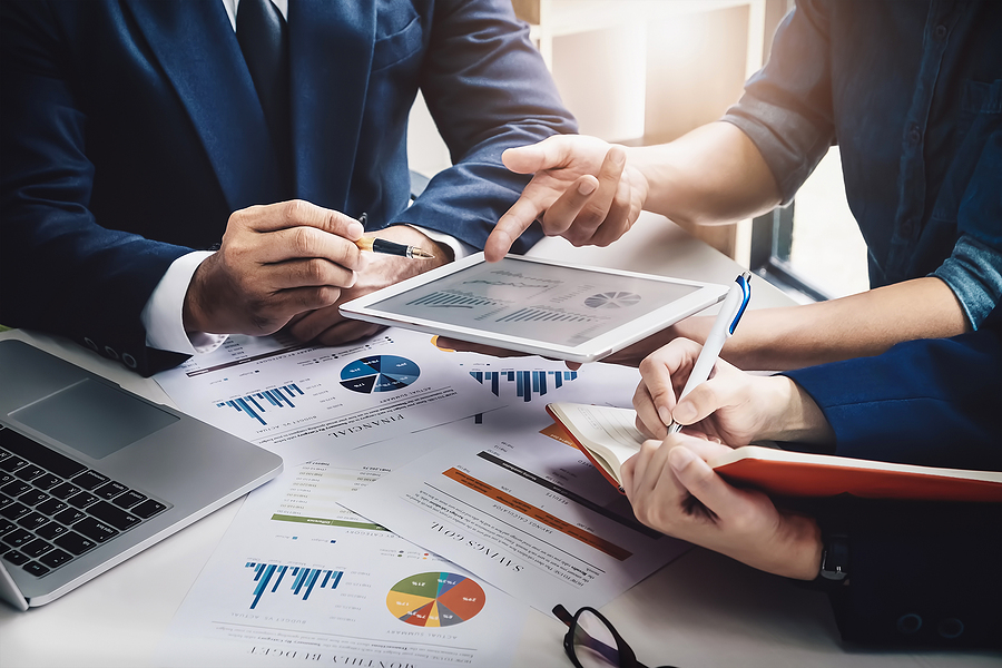 A group of investors reviewing financial documents with a concerned expression, representing the challenge of purchasing a sub sandwich franchise